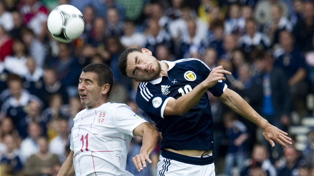 Scotland's Robert Snodgrass (right) rises in the air with Aleksandar Kolarov