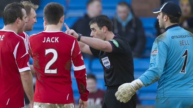 Referee Euan Norris (centre) waves away protests from Aberdeen players before booking Niall McGinn for simulation
