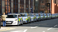 A woman takes a picture on her phone of a line of stunt vehicules parked in Cadogan Street, Glasgow